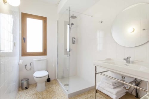 Baño moderno en apartamento Rustikalpuente con ducha de cristal, azulejos blancos, espejo redondo y ventana con marco de madera