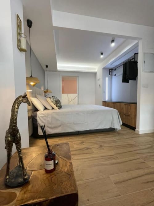 Dormitorio moderno en Agata 10 Apartamentos Alicante con cama, suelos de madera y baño ensuite