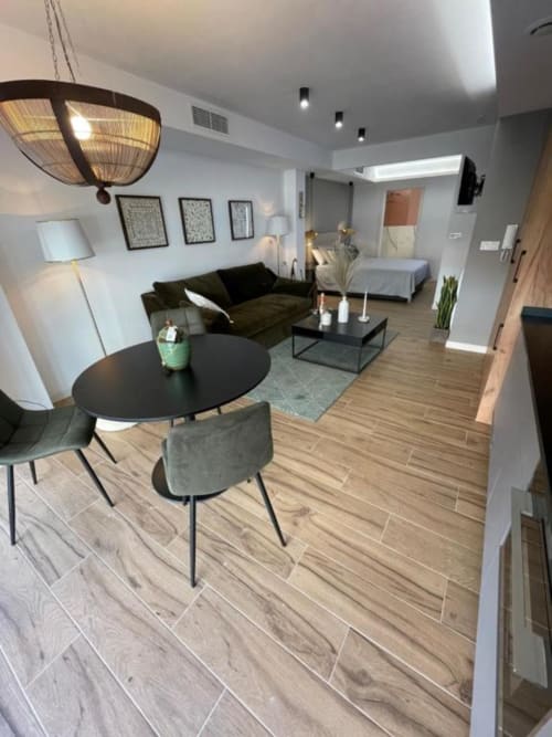 Moderna sala de estar del apartamento Agata 10 en Alicante con sofá negro, mesa de comedor y vista al dormitorio