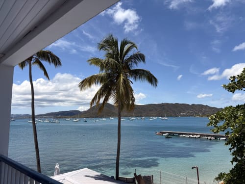 Vue de la baie Sainte-Anne depuis le balcon de l'hôtel La Dunette : palmiers, voiliers amarrés et collines verdoyantes