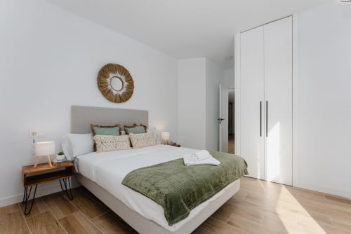 Dormitorio moderno con cabecero gris, ropa de cama verde y mesita de noche de madera en Ab Be Apartments, Fuengirola