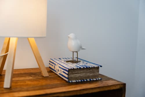 Escritorio de madera en apartamento Fuengirola con lámpara de mesa, figurita de pájaro blanco sobre libro de rayas azules y pared azul