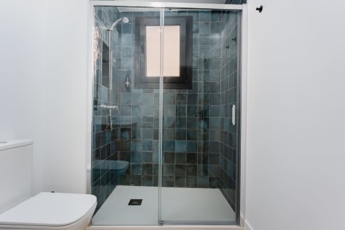Moderno baño de ducha con paredes de azulejos oscuros y mampara de cristal en Ab Be Apartments Fuengirola