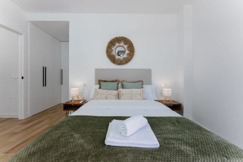 Dormitorio moderno en Ab Be Apartments de Málaga con vista al mar, cama queen, cabecero de rayas, mesitas de madera