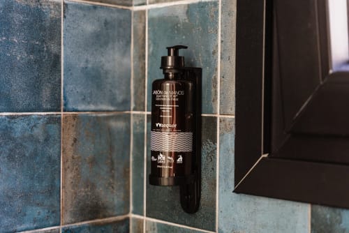Dispensador de jabón negro montado en azulejos de baño color turquesa en Ab Be Apartments Málaga