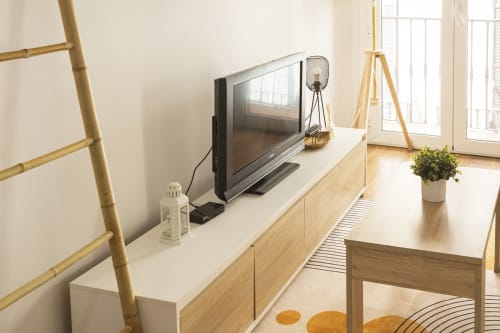 Moderno apartamento estudio en Málaga con TV de pantalla plana, muebles de madera y vistas a la ciudad desde las puertas del balcón