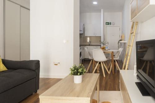Moderno estudio en Málaga con salón, comedor y cocina abiertos, mobiliario de madera y diseño contemporáneo