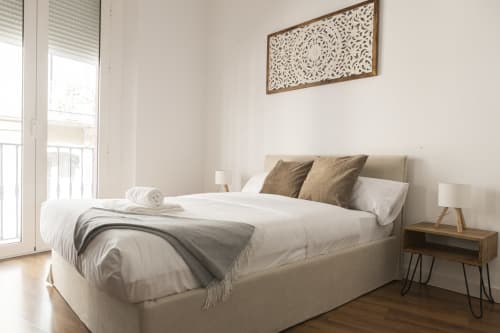 Dormitorio moderno en Ab Be Apartments de Málaga con cama tamaño queen, cabecero beige, mesitas de madera y vistas a la ciudad desde el balcón