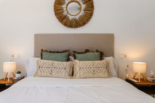 Dormitorio moderno en Ab Be Apartments en Málaga con cabecero beige, almohadas verdes y estampadas, ropa de cama blanca y madera