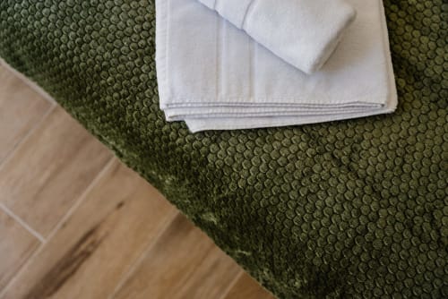 Toallas y ropa de cama blancas sobre alfombra texturizada verde en apartamento con vista al mar de Ab Be Apartments, Málaga
