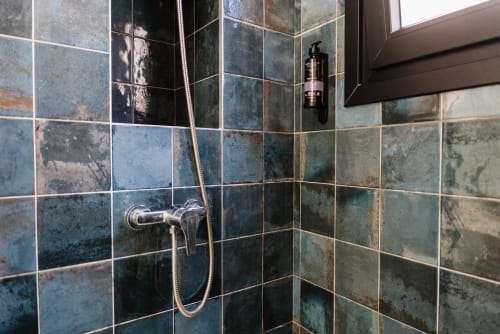 Moderna esquina de baño con azulejos azul-verdosos, accesorios cromados y artículos de tocador en Ab Be Apartments, Málaga
