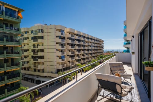 Balcón soleado con tumbonas con vistas a la costa de Málaga y edificios residenciales