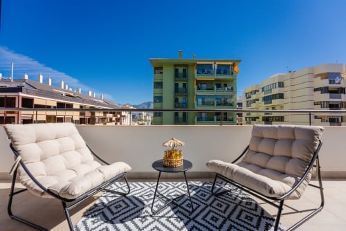 Terraza moderna en la azotea del Ab Be Apartments en Málaga con asientos confortables, edificios coloridos y vistas a la montaña