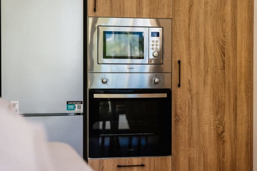 Microondas y horno de acero inoxidable empotrados en la cocina del apartamento con vistas al mar de Ab Be Apartments en Málaga