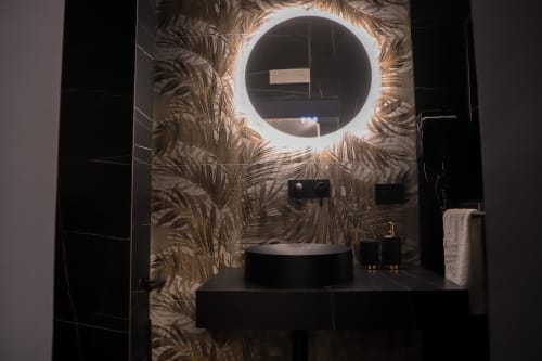 Bagno moderno nella Suite Deluxe Privitera Rooms con specchio illuminato rotondo, lavabo bianco a bacinella e carta da parati tropicale