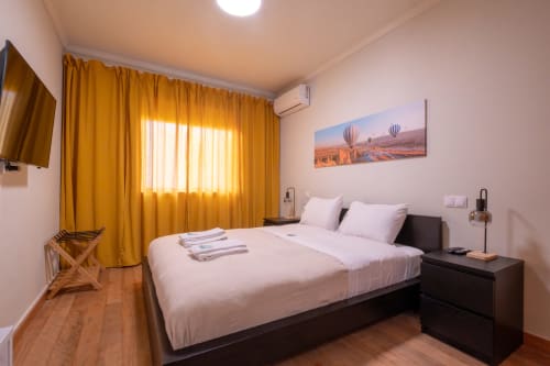 Quarto moderno no EcoHost com cama de casal, cortinas douradas, arte de balão de ar quente e vistas da cidade em Marina, Portugal