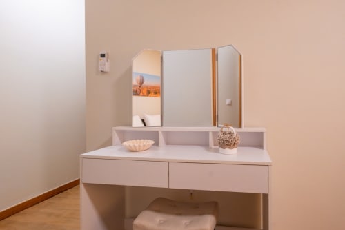 Penteadeira moderna com espelho triplo, gavetas brancas e itens de higiene no apartamento EcoHost FamilyHub em Marina