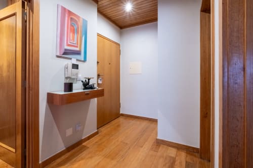 Corredor moderno do apartamento EcoHost com portas de madeira, cantinho do café, arte colorida, piso de madeira e paredes brancas