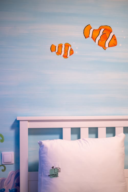 Dois papagaios de peixe-palhaço acima de uma cama com moldura rosa no apartamento familiar do EcoHost com vista da cidade