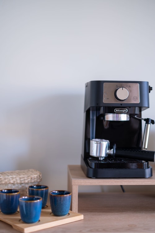 Máquina de espresso DeLonghi e xícaras de cerâmica azul no apartamento EcoHost, café pronto para usar