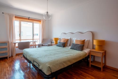 Quarto luminoso na EcoHost com cama de casal, criados de madeira, varanda com vista para o oceano e móveis modernos em Portugal