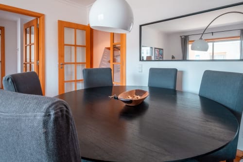 Mesa de jantar moderna com cadeiras teal e luminária branca pendente no apartamento EcoHost OceanGreen com portas de moldura laranja