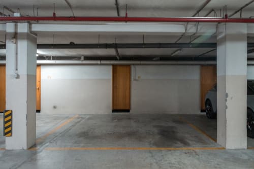 Garagem de estacionamento subterrânea do EcoHost em Portugal com vagas numeradas, piso em concreto e pilares brancos