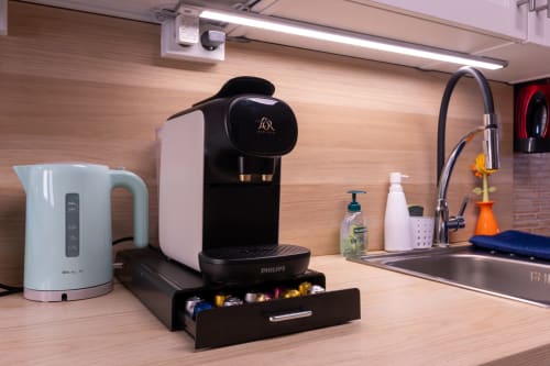 Bancada de cozinha EcoHost Perafita com máquina de café Philips, chaleira branca, pia e produtos de higiene veganos