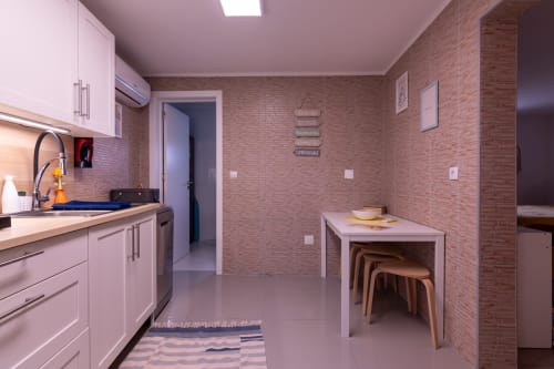 Cozinha e sala de jantar moderna com armários rosa, paredes de tijolos e bancos de madeira na Yellow House EcoHost Perafita