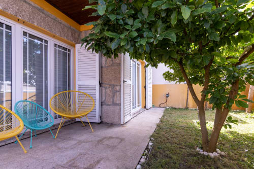 Assentos coloridos no pátio da Perafita Yellow House com jardim, cadeiras de terraço e vegetação exuberante com vista para a área externa