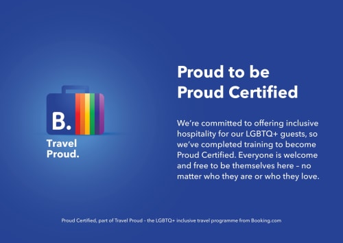 Emblema de certificação Travel Proud com cores do arco-íris em fundo azul, promovendo hospitalidade LGBTQ+ inclusiva no EcoHost