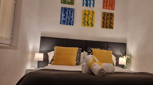 Moderna habitación de Casa Román Sport en León con cabecero oscuro, almohadas amarillas y cuadros coloridos sobre la cama