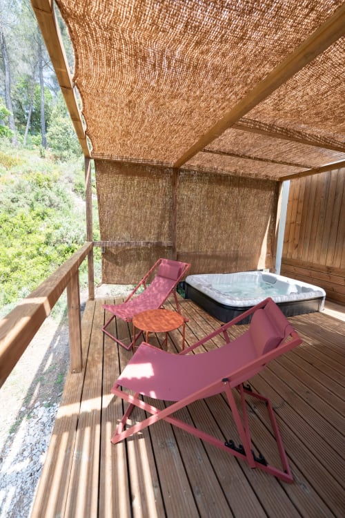 Outdoor spa deck at Le chant des pins Lodge with hot tub, lounge chairs, and woven shade canopy overlooking mountains in
