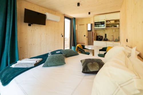 Modern lodge room at Le chant des pins with wooden interior, bed, kitchenette, TV, and terrace access in