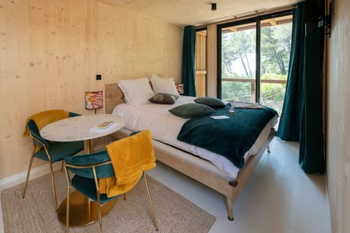 Modern wooden lodge bedroom at Le chant des pins with bed, desk, forest views, teal accents