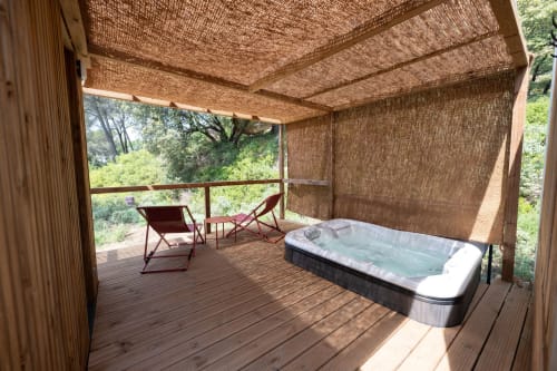 Luxury outdoor deck with hot tub, lounge chairs, and woven shade at Le chant des pins Lodges & Spas
