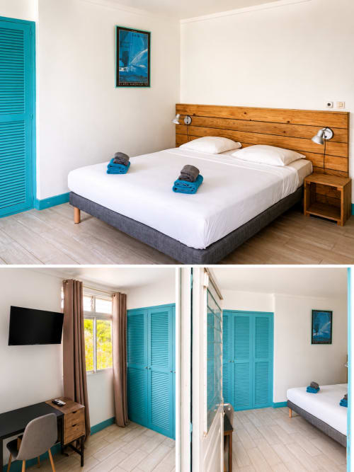 Chambre moderne à La Dunette à Sainte-Anne avec lit en bois, draps blancs, portes jalousie turquoise, télévision écran plat