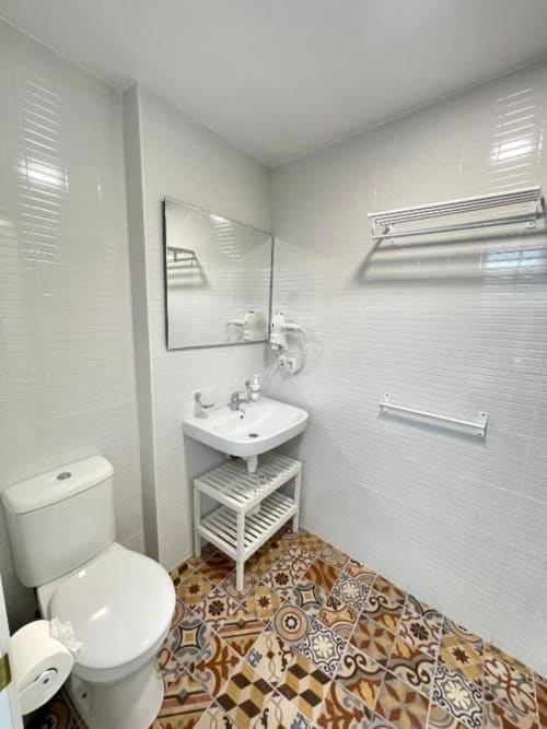 Baño moderno en Hotel Boutique Galeon de Calpe con azulejos blancos tipo metro, lavamanos de pedestal, inodoro y baldosas de diseño