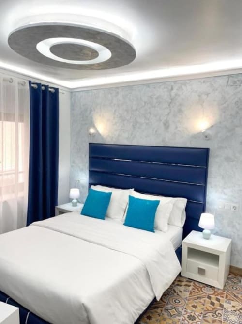 Moderna sala de estar en Hotel Boutique Galeon de Calpe con cabecero azul marino, detalles turquesa y lámpara de techo circular