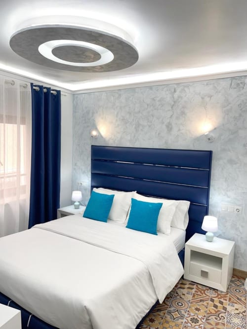 Moderno dormitorio doble en Hotel Boutique Galeon de Calpe con cabecero azul marino, ropa de cama blanca y almohadas turquesas
