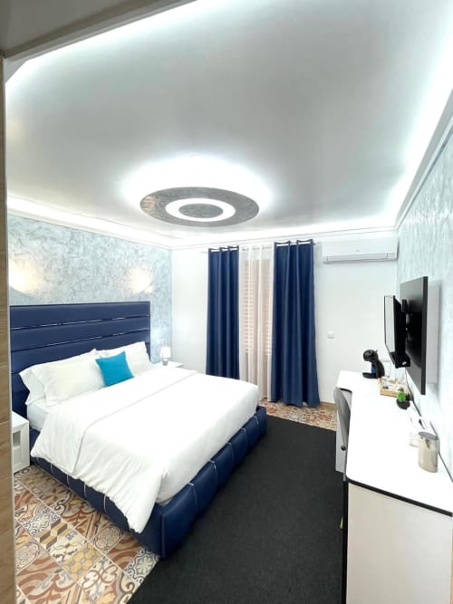 Moderno dormitorio doble en Hotel Boutique Galeon de Calpe con cama azul marino, iluminación LED en techo, TV y cortinas azules