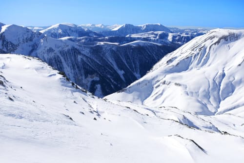 Snow-covered Alpine mountains and valleys near Hôtel la Source in La Foux, France under clear blue sky