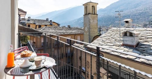 Colazione in balcone con vista sulle montagne di Locana, tetti di ardesia e campanile in pietra delle Alpi italiane