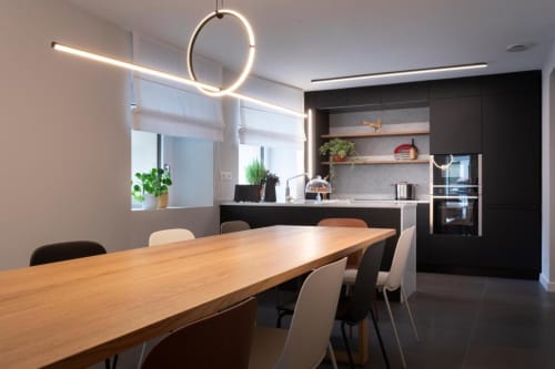 Zona cucina-living moderna di Camere d'Aria, Locana con tavolo in legno, armadiatura nera e illuminazione a sospensione
