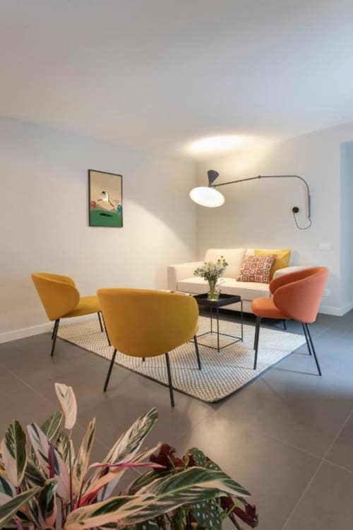 Elegante lounge della struttura Camere d'Aria a Locana con sedie colorate, divano color crema e luminosità naturale