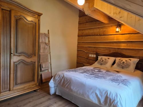 Chambre rustique à la Mise de Surcey avec poutre apparente, lit queen, coussins ourson, armoire en bois et plafond mansardé