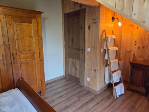 Chambre rustique à La R'Mise de Surcey avec mobilier en bois, porte-serviettes échelle et vue sur le jardin à Eternoz