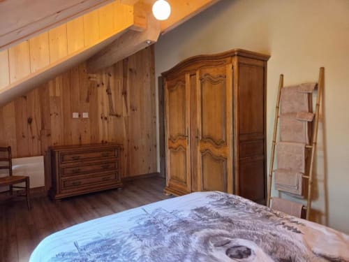 Chambre rustique à La R'Mise de Surcey avec plafond à poutres apparentes, armoire ornementale et mobilier traditionnel à Eternoz