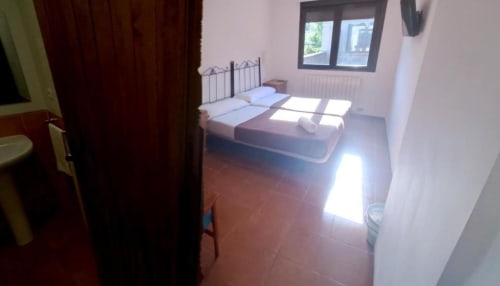 Habitación doble luminosa con cabecero de forja y suelo cerámico en Hostal Monterde de Albarracín