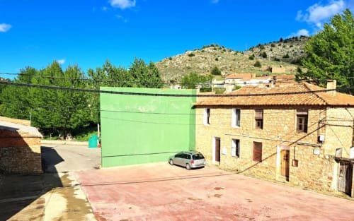 Vista exterior del entorno rural de Monterde de Albarracín con casas de piedra y paisaje de montaña